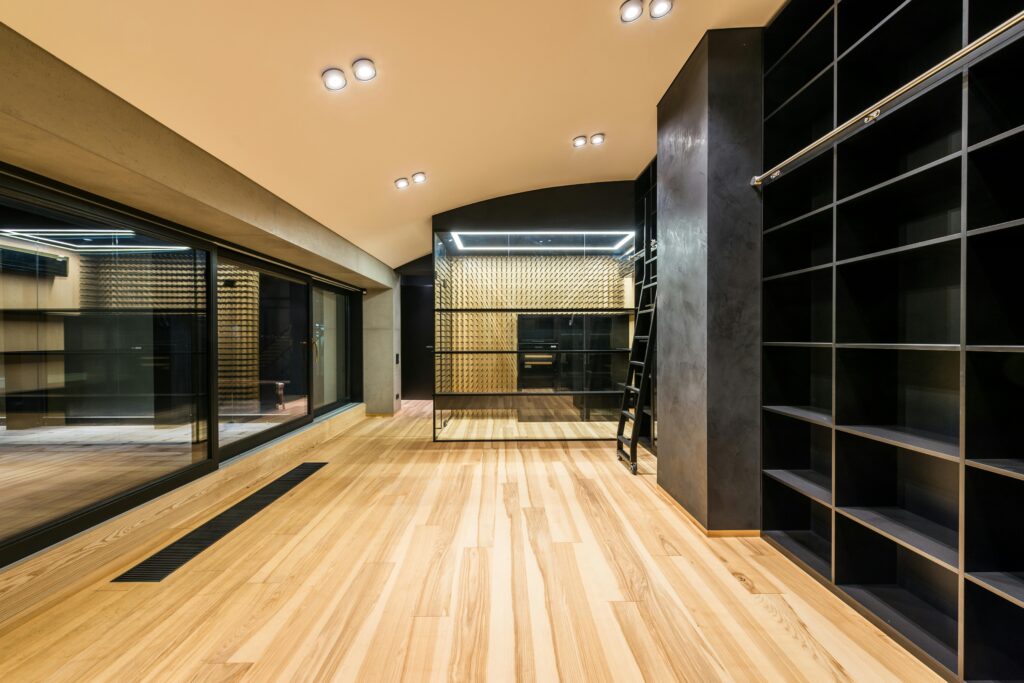 Wine cellar with ladder and shelves reflecting in mirrors on parquet under lamps in building